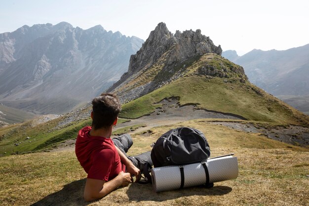 Männlicher Reisender, der in den Bergen wandert, während er seine wichtigsten Sachen im Rucksack dabei hat