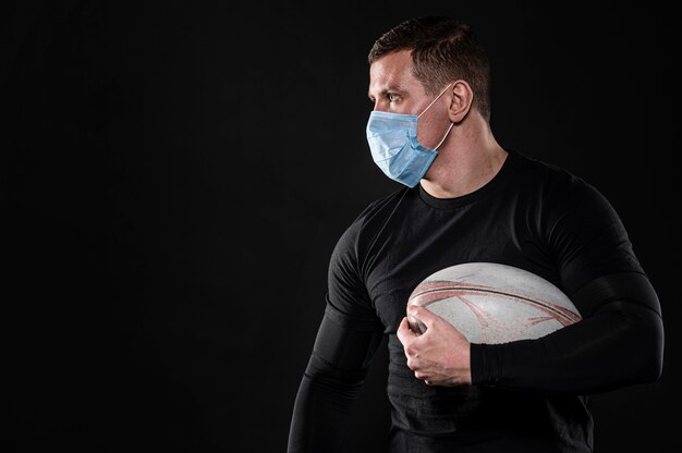 Männlicher Rugbyspieler mit medizinischer Maske und Kopienraum