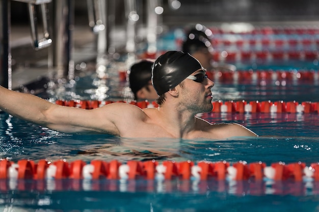 Männlicher Schwimmer, der den Rand eines Schwimmbades hält