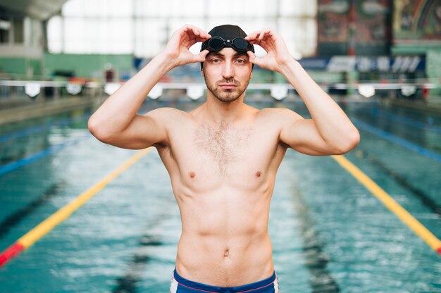 Männlicher Schwimmer der Vorderansicht, der auf Schwimmbrille sich setzt