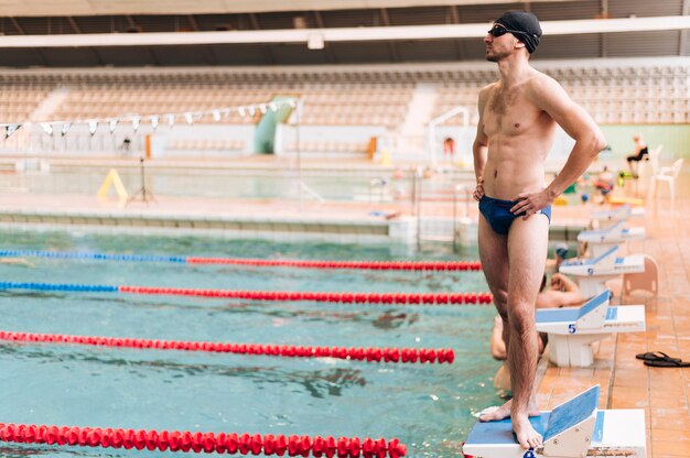 Männlicher Schwimmer des hohen Winkels, der auf Poolrand steht