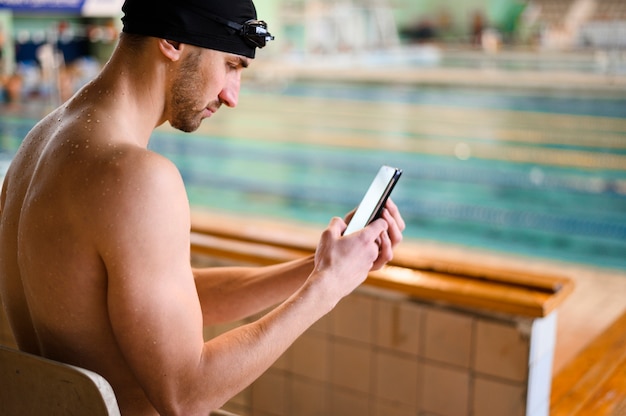 Männlicher Schwimmer des hohen Winkels, der Telefon verwendet