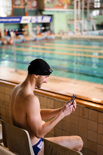 Männlicher Schwimmer des smiley, der Mobile verwendet