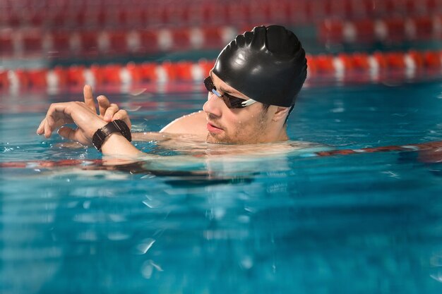 Männlicher Schwimmer schaut auf die Uhr