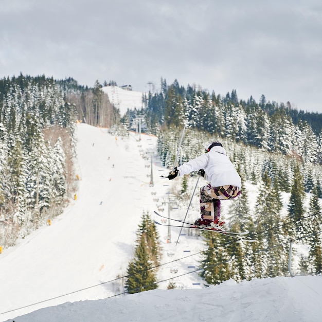 Männlicher Skifahrer, der beim Skifahren in den Bergen springt