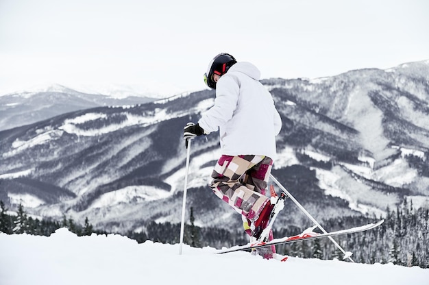 Männlicher Skifahrer, der einen schneebedeckten Hügel in den Bergen hinuntergeht