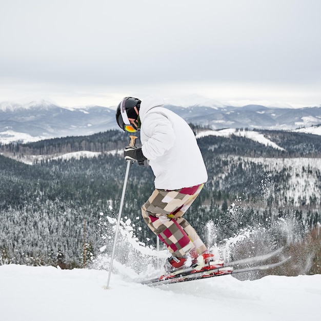 Kostenloses Foto männlicher skifahrer, der in den schönen winterbergen ski fährt