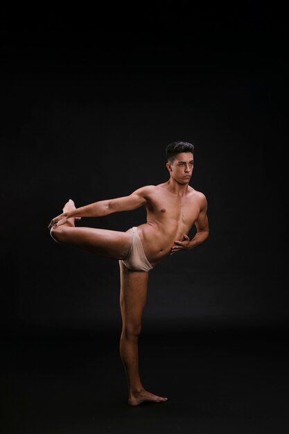 Männlicher Tänzer, der auf einem Bein balanciert