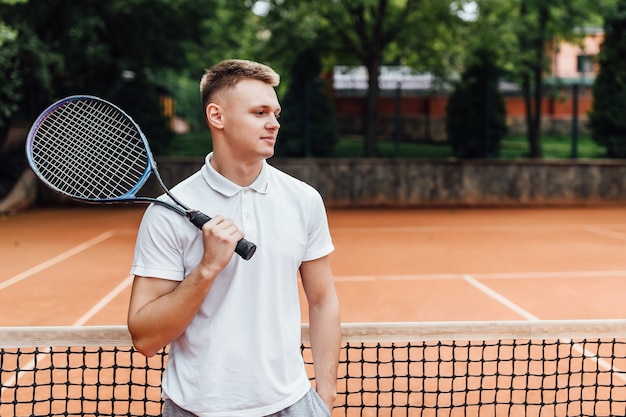Männlicher Tennisspieler auf dem Platz, der glücklich schaut, während er Schläger hält.