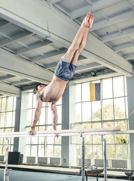 Männlicher Turner, der Handstand auf Barren durchführt