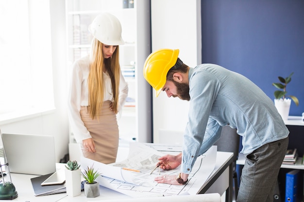 Männlicher und weiblicher Ingenieur, der an Plan im Büro arbeitet