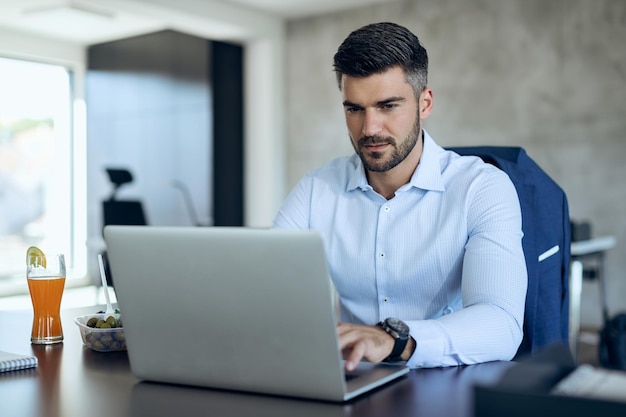 Männlicher Unternehmer, der Computer verwendet, während er im Büro arbeitet