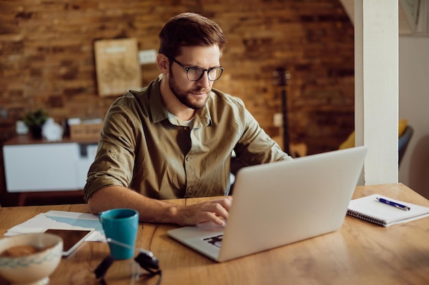 Männlicher Unternehmer, der zu Hause an einem Computer arbeitet