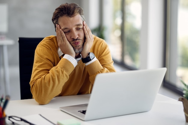 Männlicher Unternehmer schickt einen Kuss während eines Videoanrufs im Büro