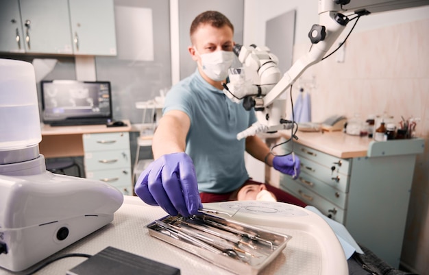 Männlicher Zahnarzt, der während des zahnärztlichen Eingriffs den Dental Explorer packt