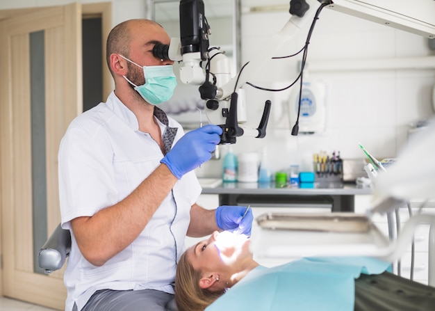 Männlicher Zahnarzt, der Wurzelkanal des weiblichen Patienten behandelt