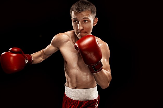 Männliches Boxerboxen mit dramatischer kantiger Beleuchtung in einem dunklen Studio