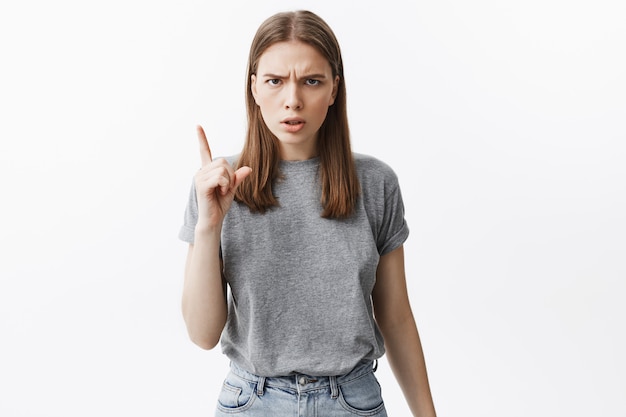 Mag das nicht mehr. Porträt des schönen dunkelhaarigen unglücklichen Mädchens in der grauen Freizeitkleidung, die mit der Hand gestikuliert, mit wütendem Gesichtsausdruck.