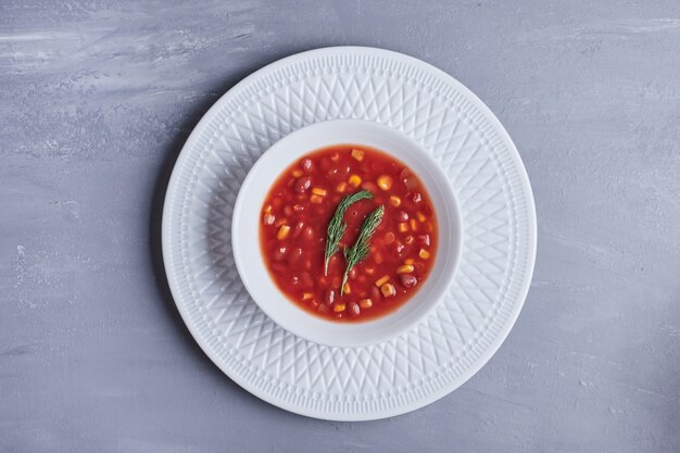 Maissuppe in Tomatensauce in einer weißen Schüssel.