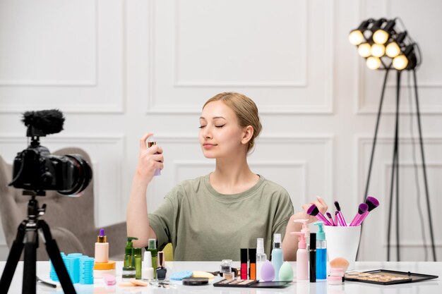 Make-up-Blogger, der Make-up-Tutorial auf der Kamera aufzeichnet, junges süßes hübsches Mädchen, das Nebel sprüht