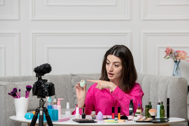 Make-up-Bloggerin, niedlich, schöne, schöne junge Frau, die mit einem Schwamm ein Video vor der Kamera aufnimmt