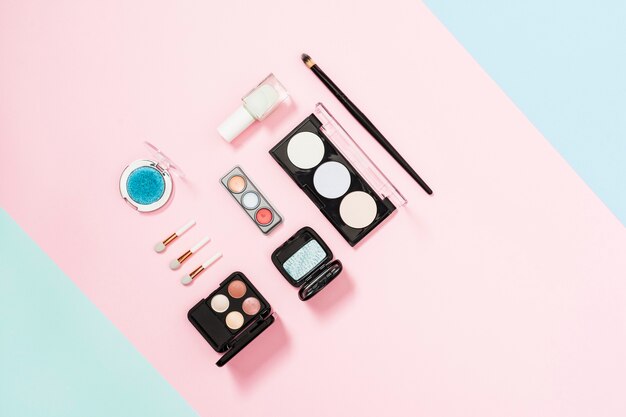 Make-upbürste und kosmetische Lidschattenpalette und kompaktes Pulver auf rosa Hintergrund