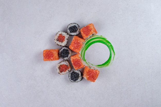 Maki, Alaska und Kalifornien Sushi rollt auf weißem Hintergrund mit grünem Kunststoffring.