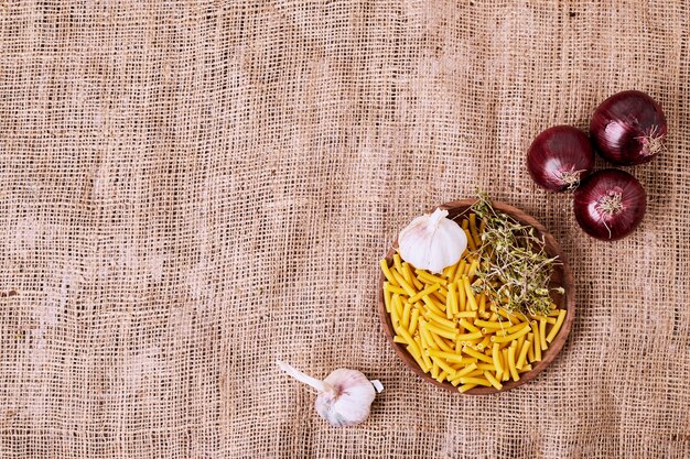 Makkaroni, Knoblauch und Zwiebeln auf brauner Oberfläche.