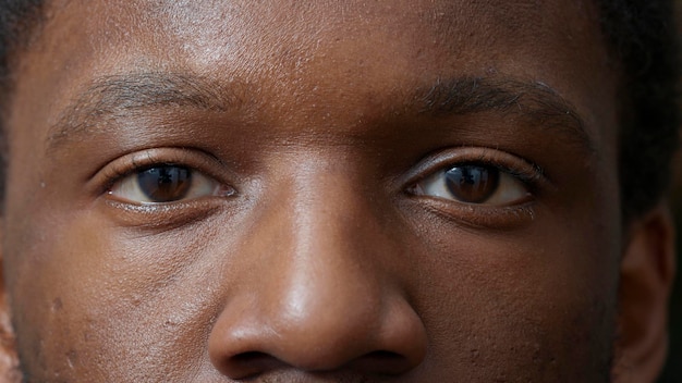 Makroaufnahme eines jungen Erwachsenen, der vor der Kamera blinzelt und Augen mit farbiger Iris, Netzhaut und Pupille zeigt. Mann, der Reflexion, gesunden Fokus und Sehvermögen betrachtet. Augenbrauen und Wimpern. Authentisches Aussehen.