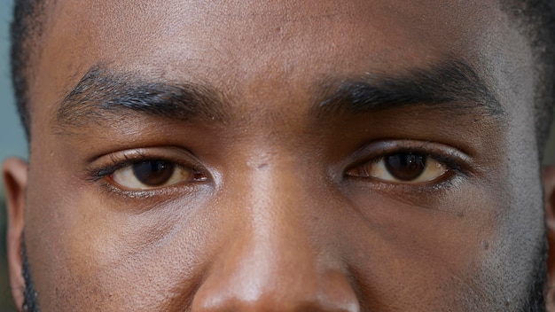 Makroaufnahme eines jungen Mannes, der braune Augen vor der Kamera zeigt, blinzelt und die Reflexion betrachtet. Person mit Augenbrauen, Wimpern und gesundem Sehvermögen mit guter Sicht und optischem Fokus. Nahansicht.
