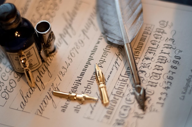 Makroaufnahme eines quill-sets und einer tintenflasche auf einem blatt papier mit kalligrafie darauf