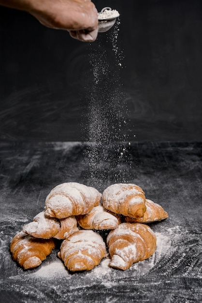 Makrobild von Croissants mit Puderzucker auf grauem Tisch.