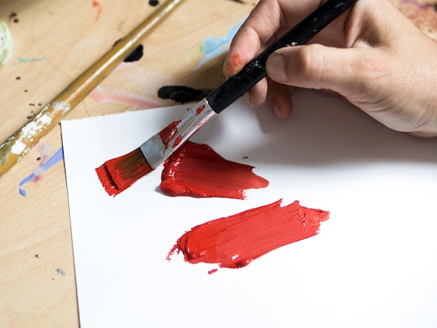 Maler des hohen Winkels mit roter Farbe auf Bürstennahaufnahme