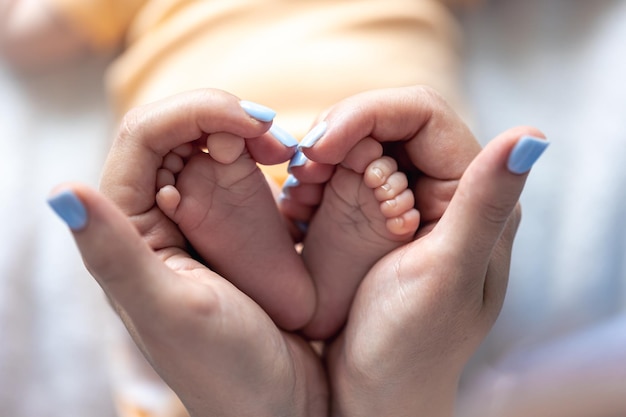 Kostenloses Foto mama hält die beine eines neugeborenen in ihren händen