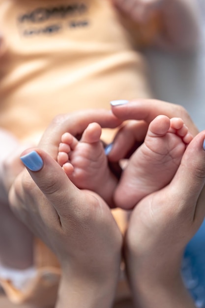 Kostenloses Foto mama hält die beine eines neugeborenen in ihren händen