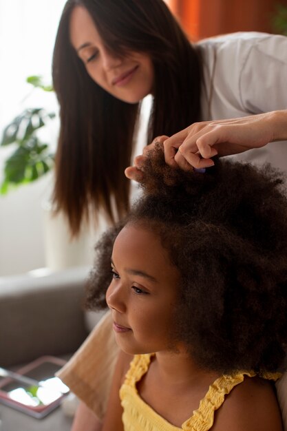 Mama hilft ihrem Kind beim Styling von Afro-Haaren