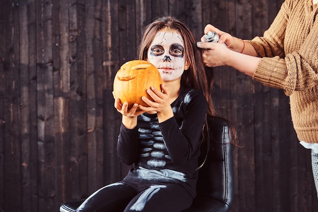 Kostenloses Foto mama macht haarstyling mit einem haarspray für die halloween-party. halloween-konzept.