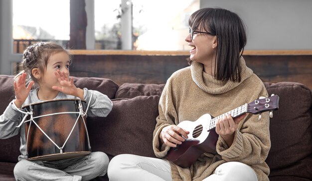 Mama spielt mit ihrer Tochter zu Hause. Unterricht auf einem Musikinstrument. Kinderentwicklung und Familienwerte. Das Konzept der Freundschaft und Familie der Kinder.