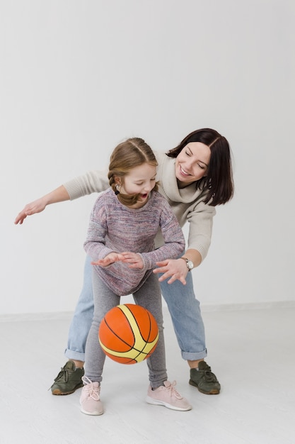 Mama und Mädchen spielen Basketball