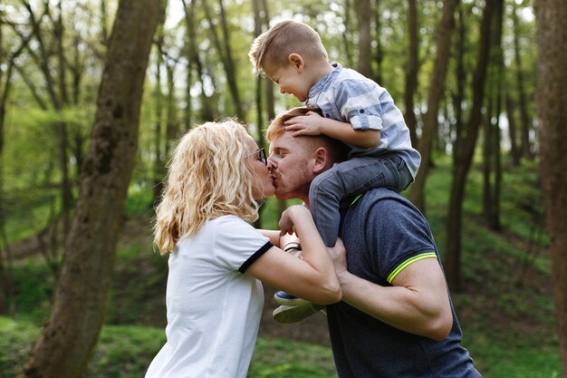 Mama und Papa küssen sich, während ihr kleiner Sohn seine Augen schließt