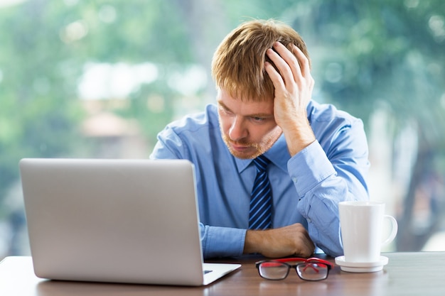 Kostenloses Foto man berührt seine haare während blick auf den laptop