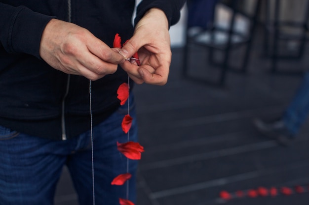 Man legt rote Rosenblätter auf den Faden