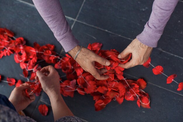 Man legt rote Rosenblätter auf den Faden