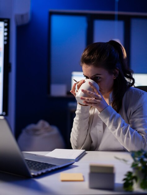 Manager mit Internet-Videokonferenz, die in einem professionellen Start-up-Geschäftsbüro sitzt und eine Tasse Kaffee trinkt