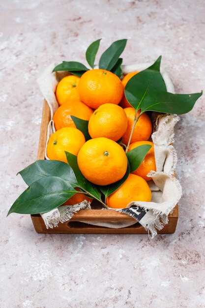 Mandarinen (Orangen, Klementinen, Zitrusfrüchte) mit grünen Blättern auf Betonoberfläche mit Kopienraum