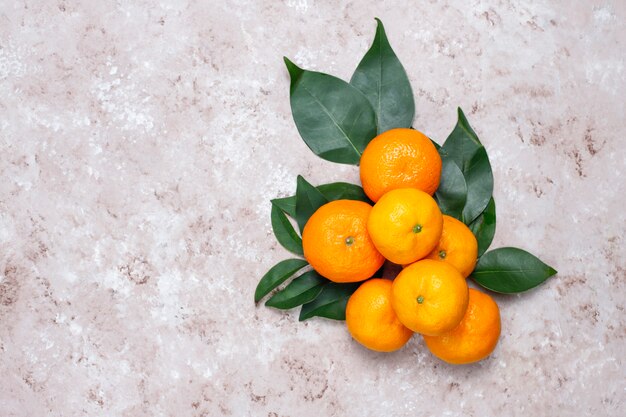 Mandarinen (Orangen, Klementinen, Zitrusfrüchte) mit grünen Blättern auf Betonoberfläche mit Kopienraum