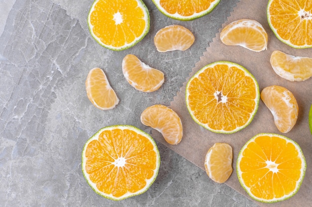 Mandarinensegmente und geschnittene frische Zitrone auf Marmoroberfläche.