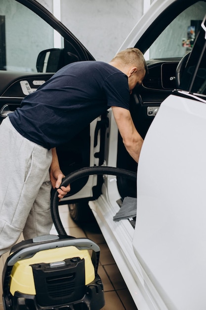 Mann am Auto säubert das Auto im Inneren