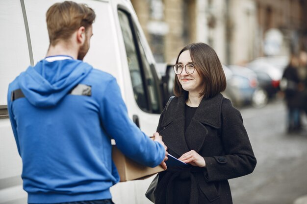 Mann am LKW. Mann in einer Lieferuniform. Lieferbote mit Paket im Freien