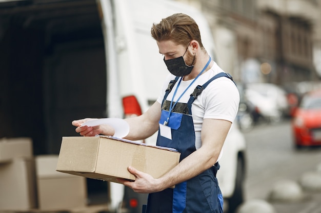 Mann am lkw. mann in einer lieferuniform. mann in einer medizinischen maske. coronavirus-konzept.